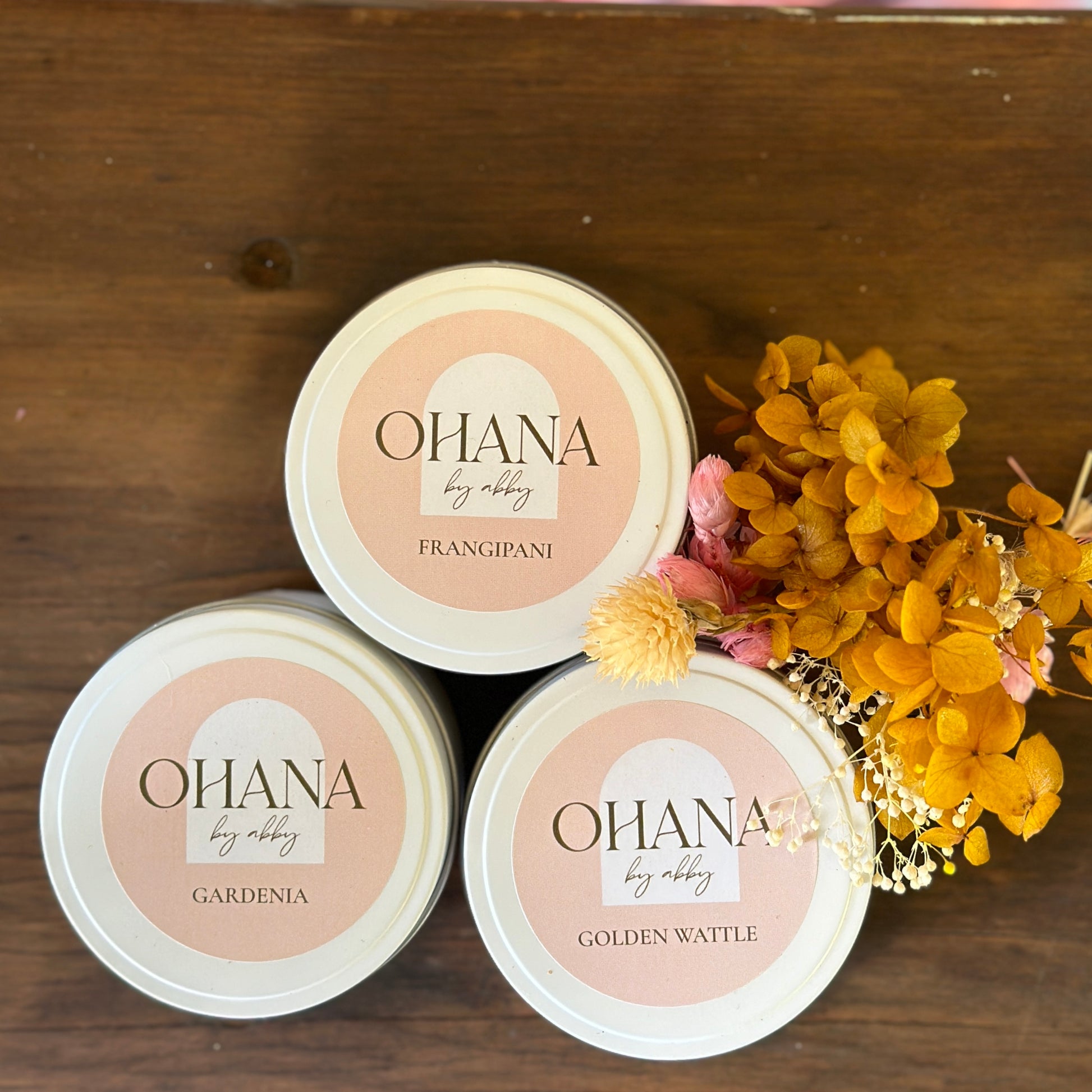 three white tin candles with floral scents and a mini bunch of dried flowers