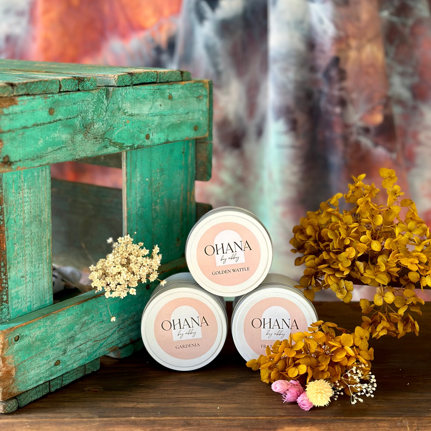 Three tins of floral scented soy wax candles with dried flowers.