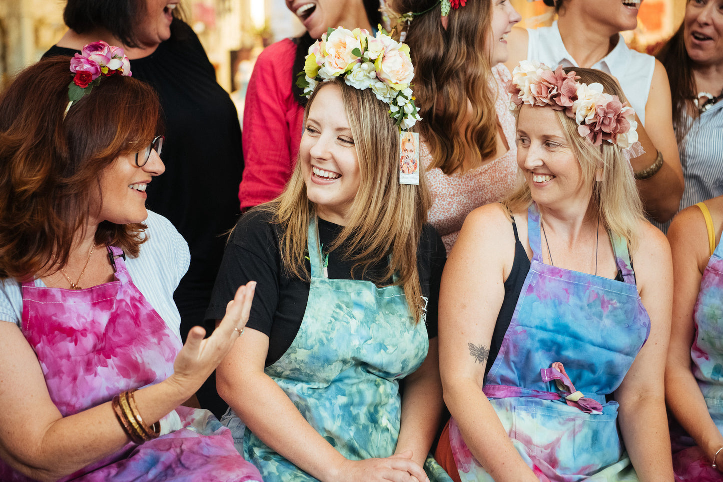 a bunch of women wearing ice dye aprons in rainbow colours