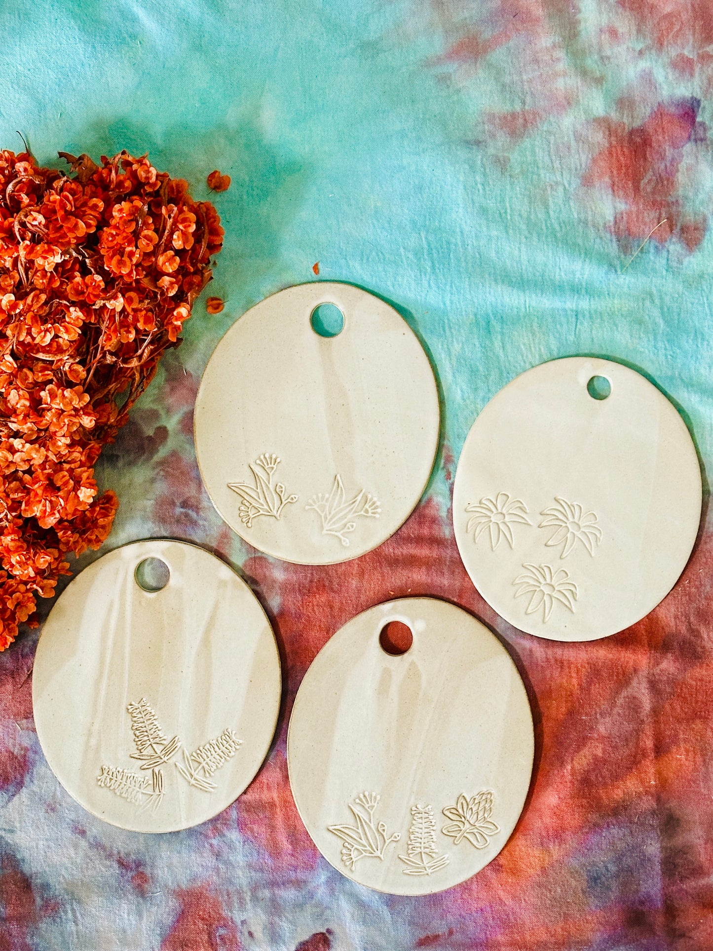 Four oval shaped handmade ceramic cheese platters with gum leaves and flowers imprinted into the clay.