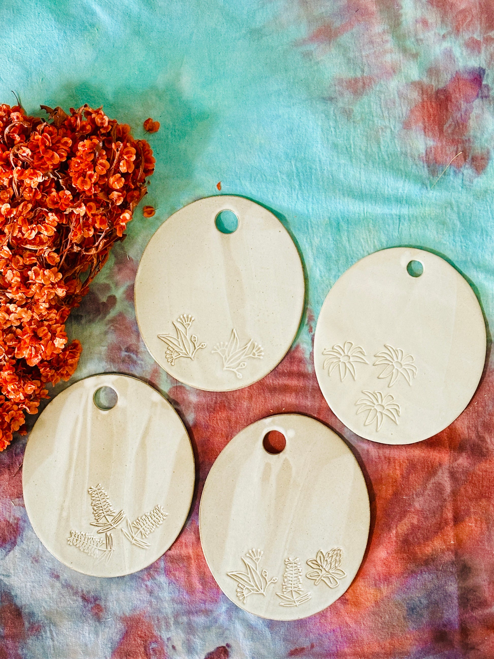 Four oval shaped handmade ceramic cheese platters with gum leaves and flowers imprinted into the clay.