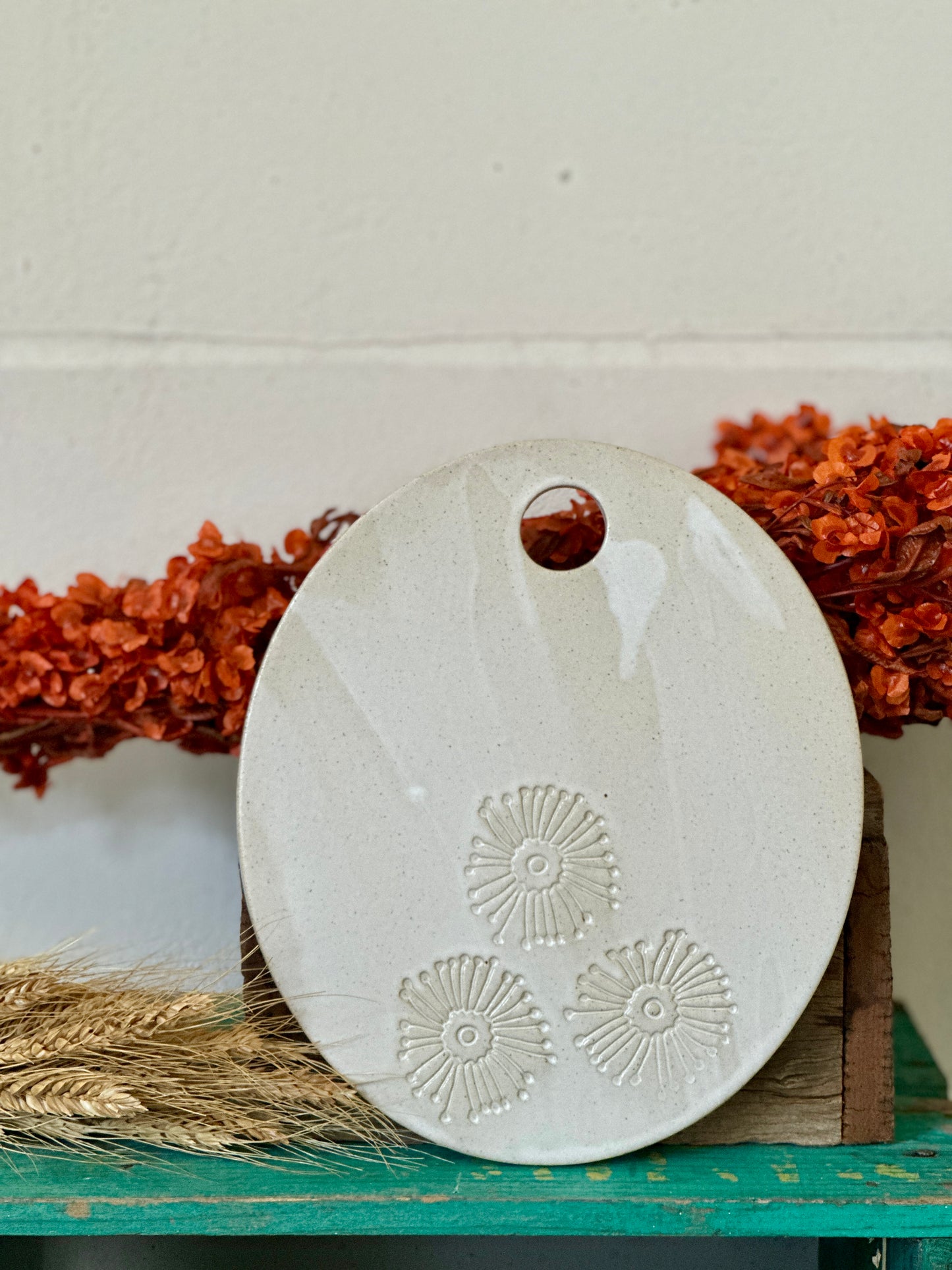 An oval shaped handmade ceramic cheese platter with gum blossom flowers imprinted into the clay.