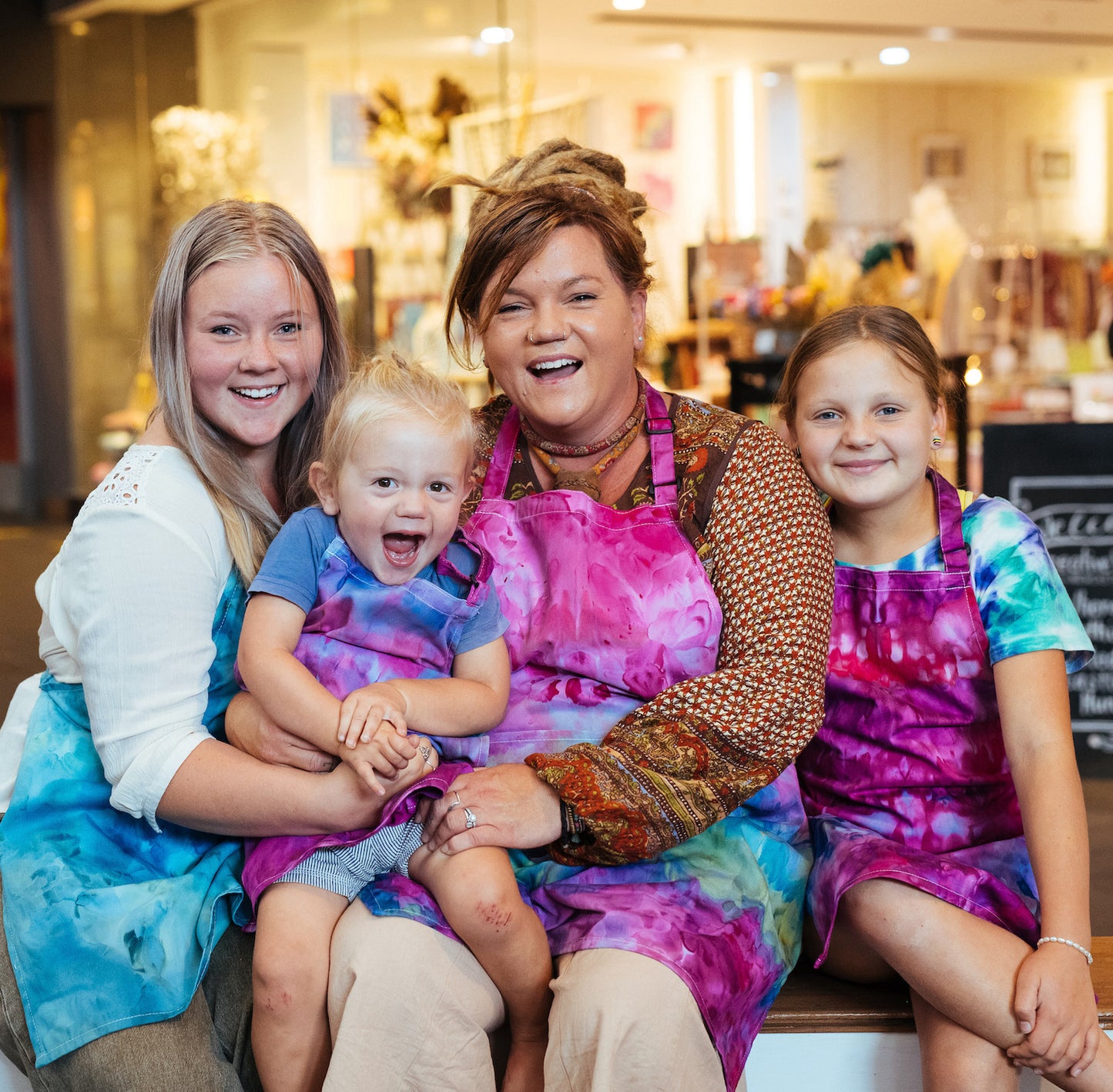 A family of four wearing colourful ice dyed aprons